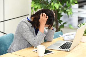 PC作業で疲れて頭を抱えている女性